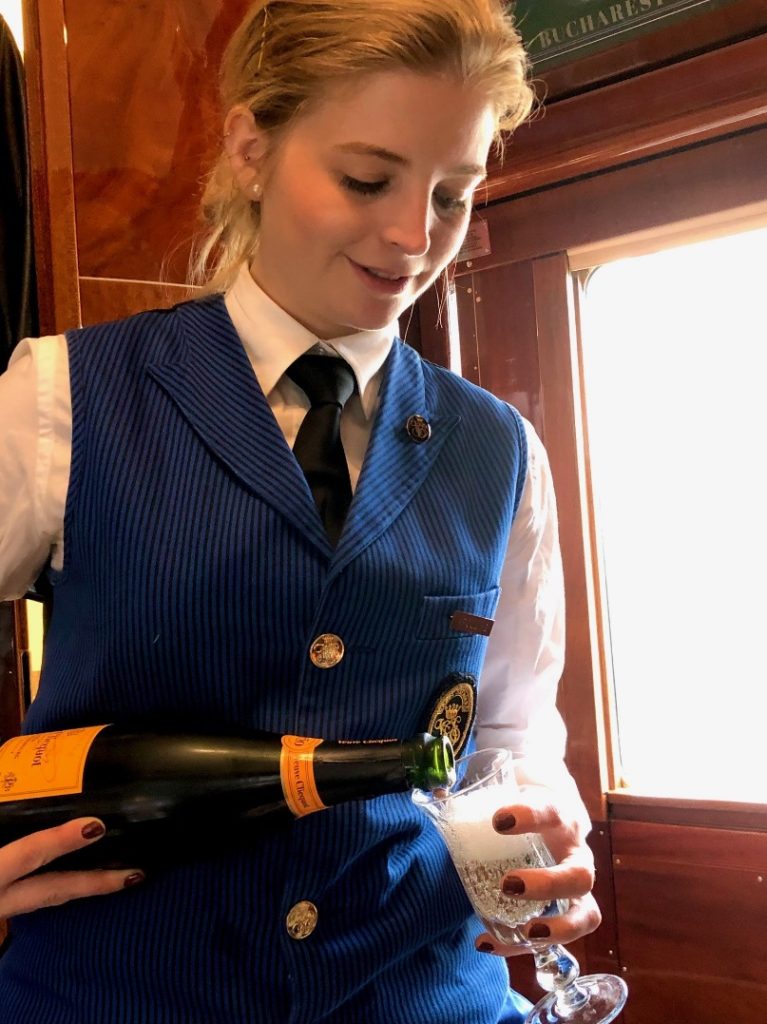 A young woman pouring champagne on the Venice-Simplon Orient Express 