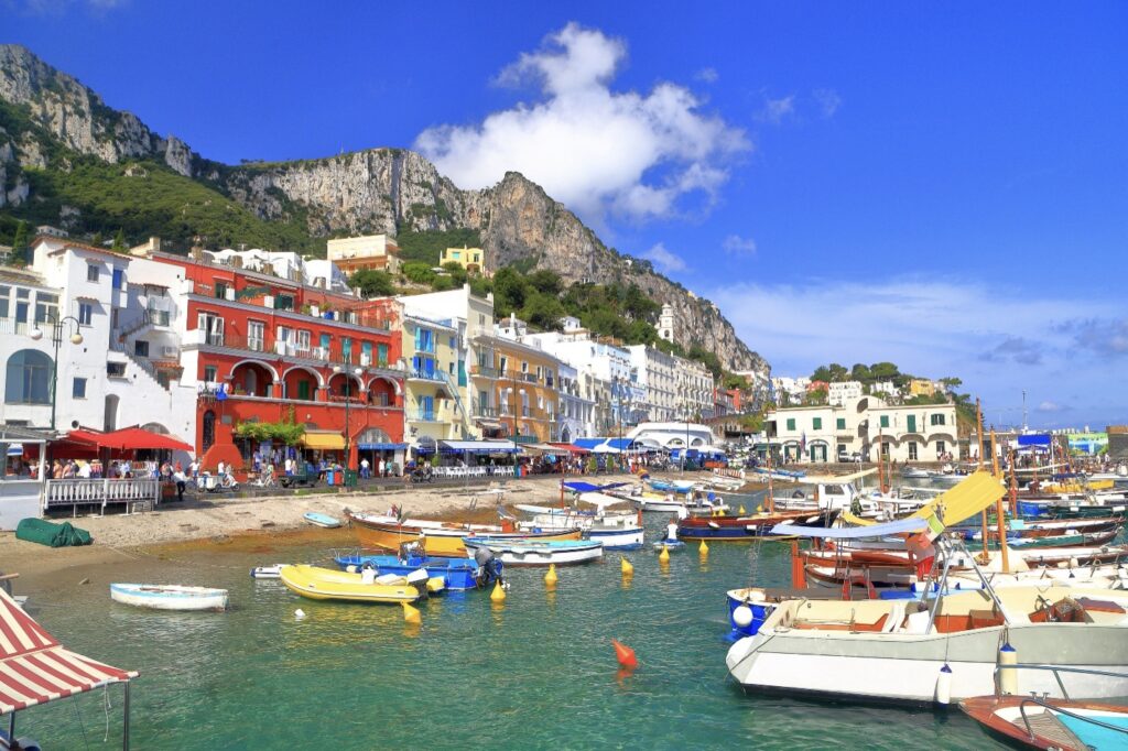 Colorful boats and buildings along dramatic cliffs.