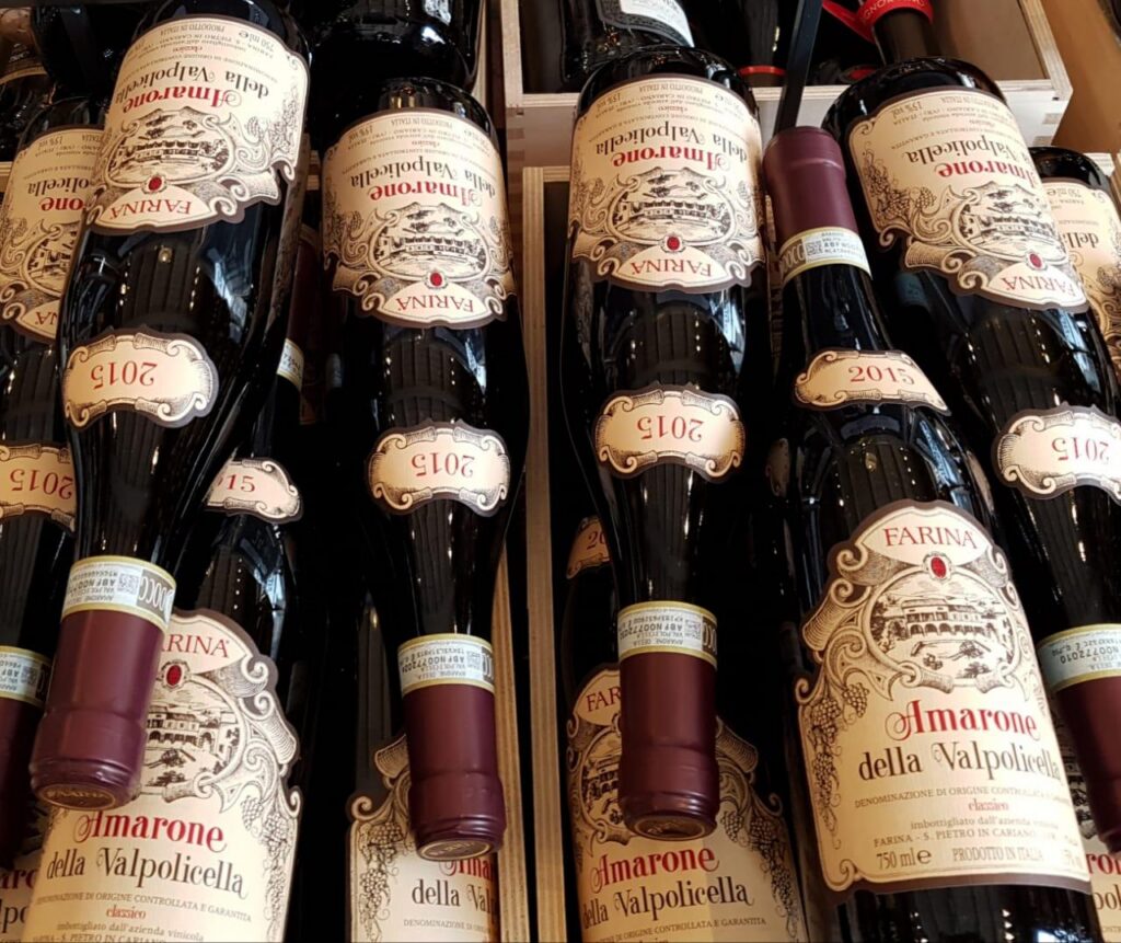 Several bottles of Amarone della Valpolicella wine with vintage labels, arranged closely together in a wooden crate display.