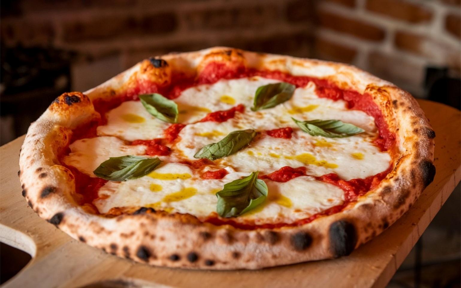 Classic Neapolitan Margherita pizza with fresh mozzarella, tomato sauce, basil leaves, and olive oil on a charred, wood-fired crust, often considered the best pizza in Italy.